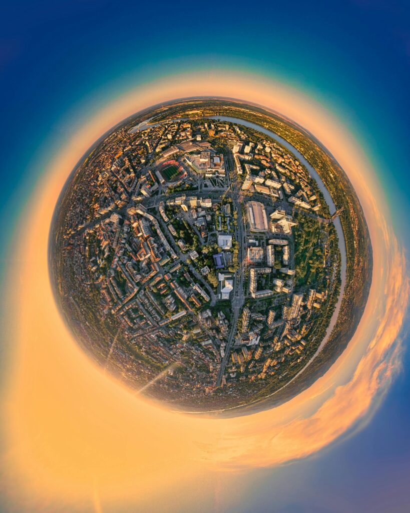 A stunning aerial fisheye view of Novi Sad, showcasing its vibrant cityscape under a colorful sky.
